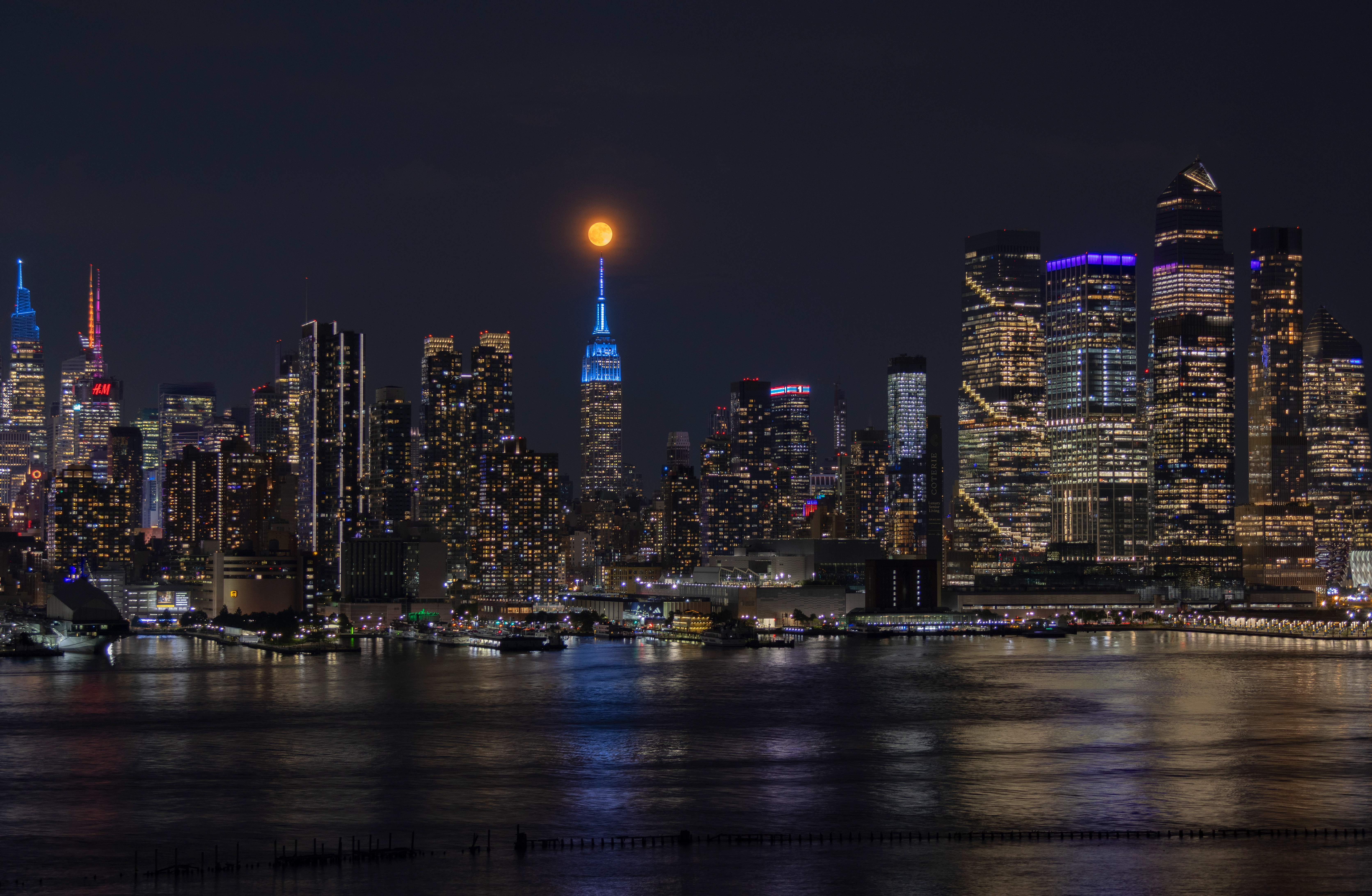A photograph of the Strawberry Moon above the tip of the Empire State Building.