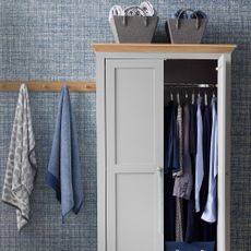 room with blue textured wall cloths on cupboard and hanging towels
