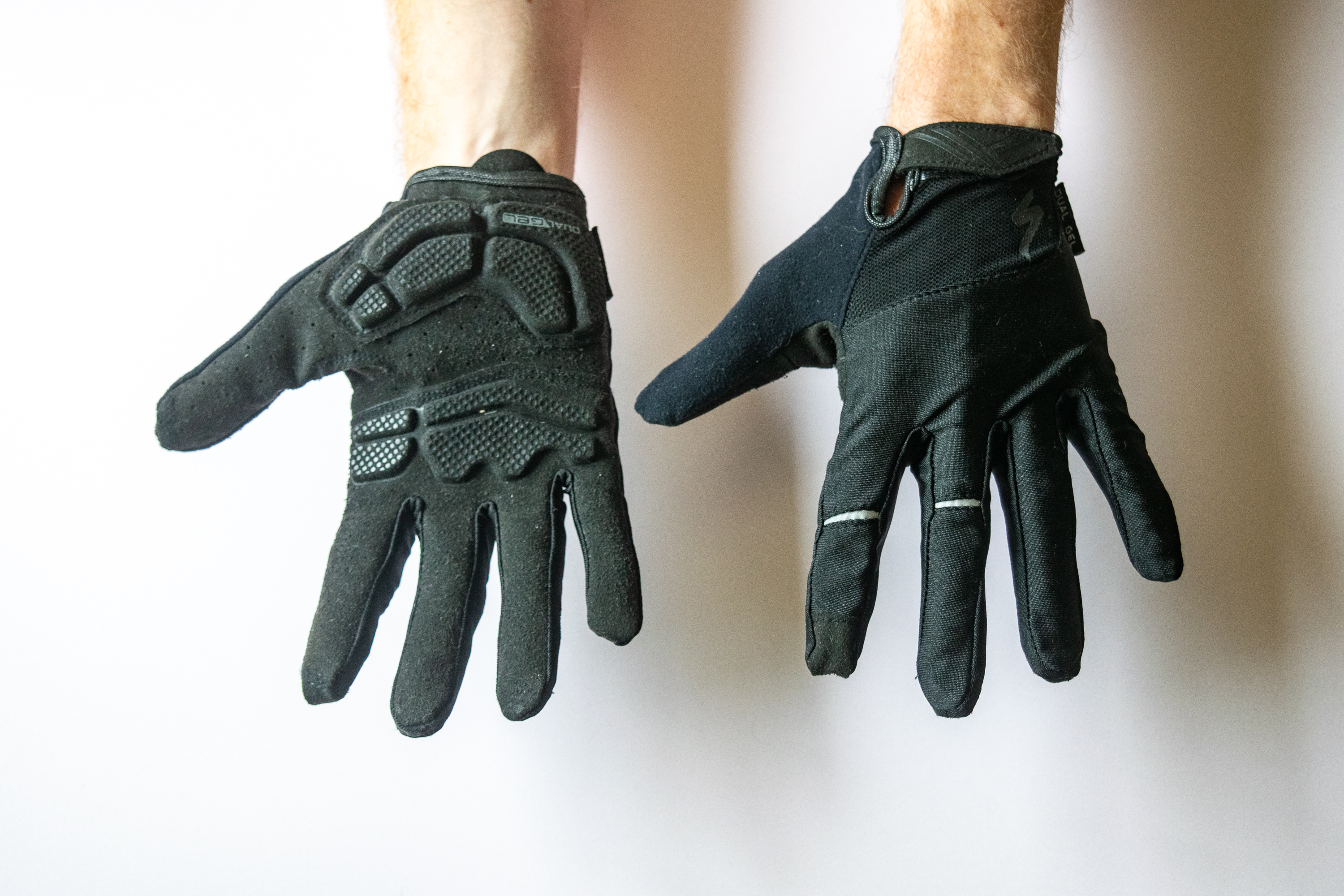 A rider wearing Specialized Body Geometry Dual Gel Gloves with hands showing the palm and face of the gloves