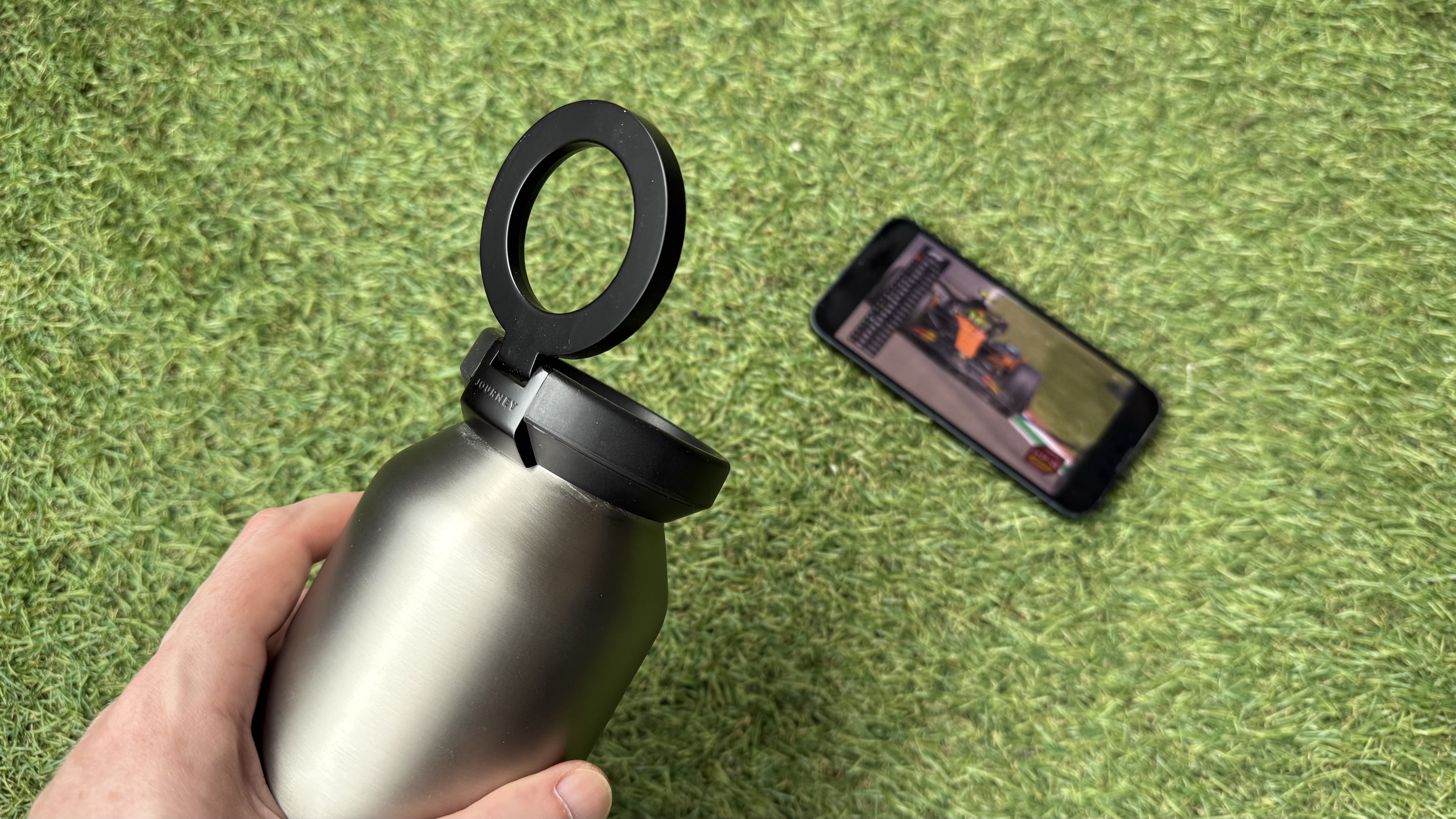 The Journey Reevus water bottle on a faux-grass surface