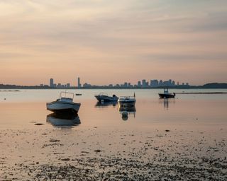 Calm dusk shot of Hough's Neck beach in Quincy Massachusetts with Boston skyline in the distance.