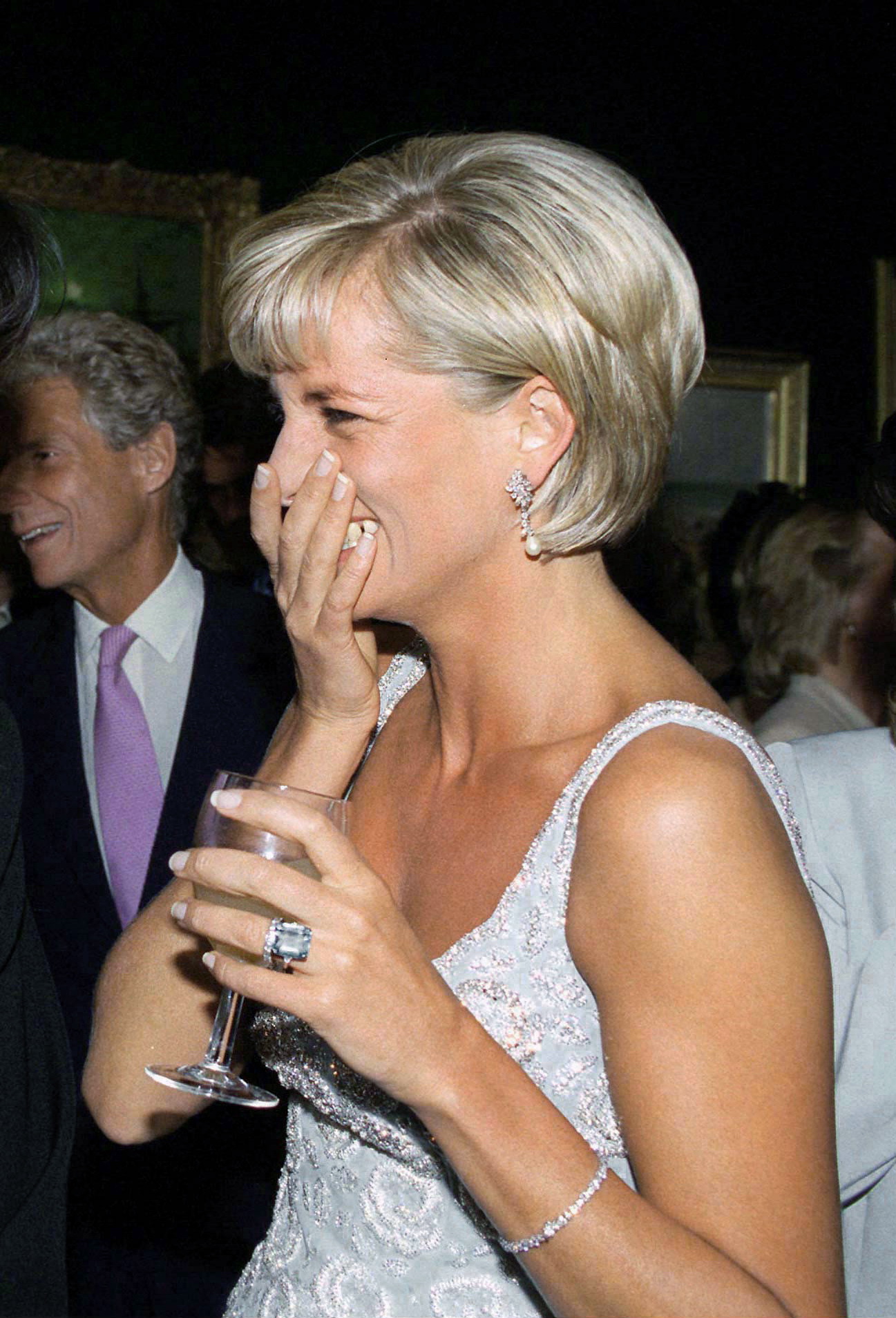 Princess Diana covering her mouth and laughing, holding a wine glass