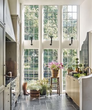 A galley kitchen with floor-to-ceiling windows and light wood farmhouse cabinetry