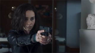A still from Secret Invasion, a TV show from Marvel Studios. A lady with shoulder length dark hair and wearing a leather jacket is pointing a hand gun just off to the right.