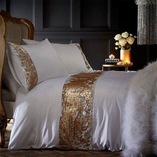 bedroom with white bedsheet and pillows with gold to silver border