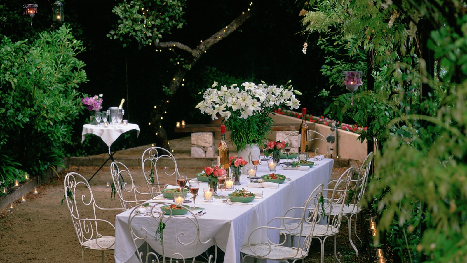 garden table with metal chairs white tablecloth and candle lanterns