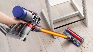 Dyson V8 vacuuming cereal from a hard wood floor