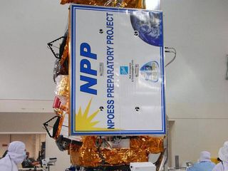 In a clean room inside the Astrotech Payload Processing Facility at Vandenberg Air Force Base in California, Ball Aerospace technicians rotate NASA’s National Polar-orbiting Operational Environmental Satellite System Preparatory Project (NPP) spacecraft into the vertical position during a solar array frangible bolt pre-load verification test.