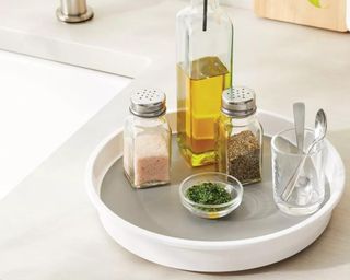 White Lazy Susan with glass jars of herbs and bottles of condiments on it