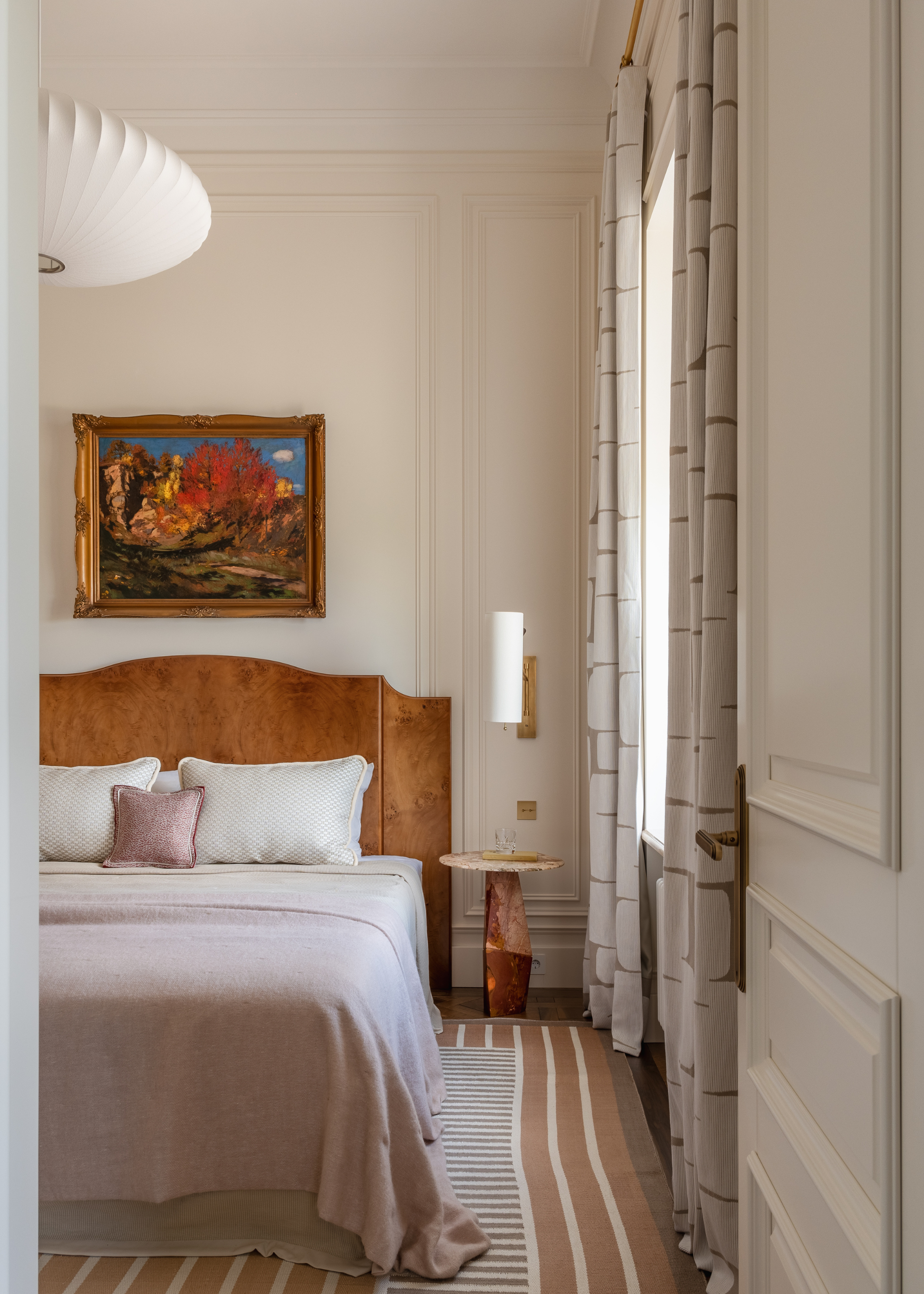 A beautiful bedroom with wall sconces, framed art, a wooden headboard, and a pendant lantern