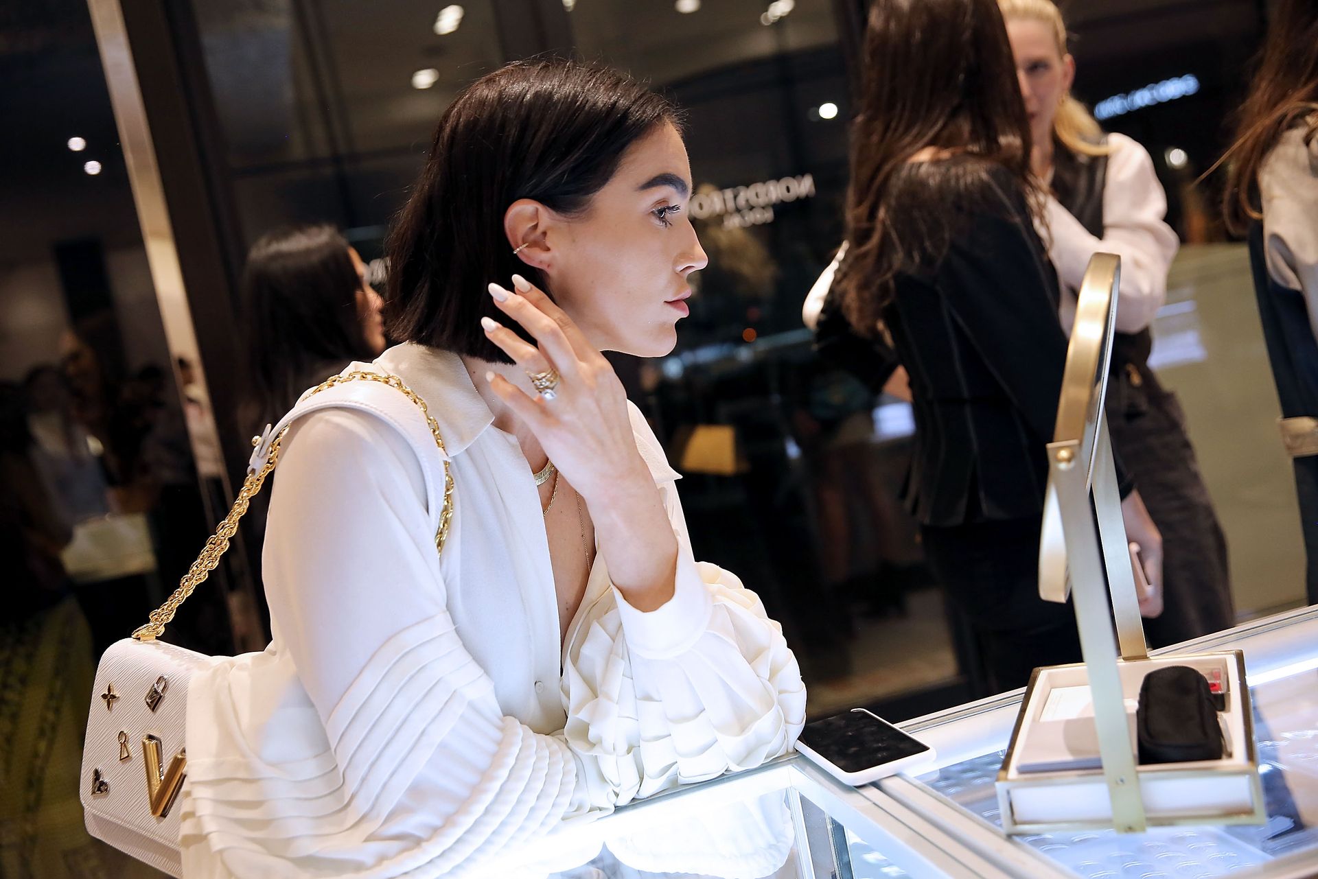 A young woman shops at Nordstrom, and looks in the mirror as she tries on accessories.