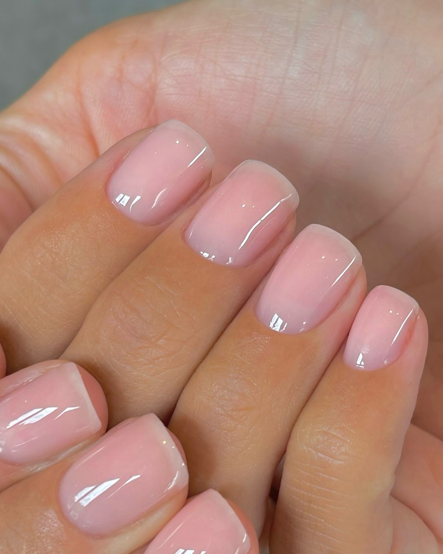 A close-up of sheer, lipgloss nails
