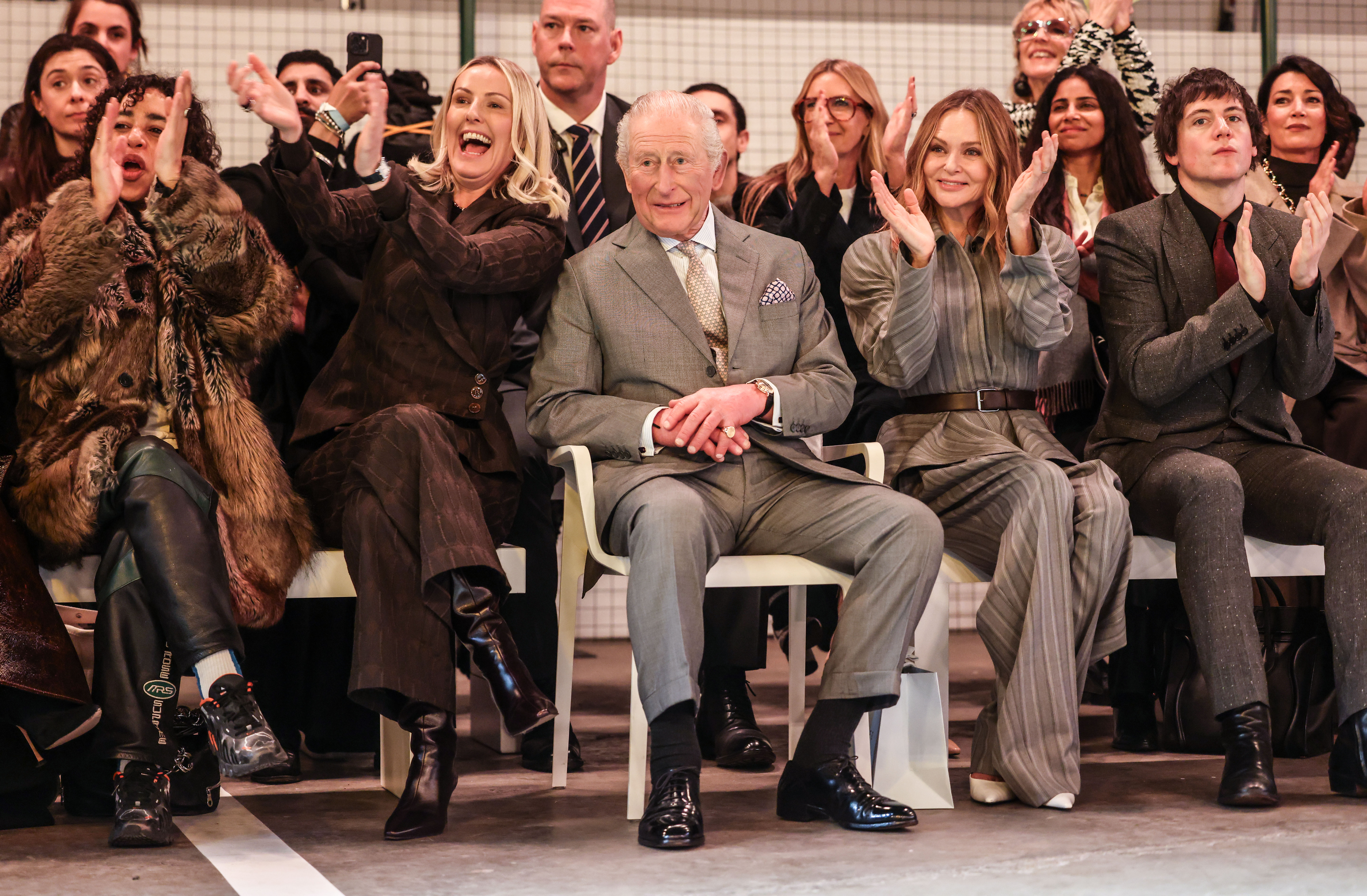 The King sitting front row at a London Fashion Week catwalk show in a greige suit