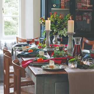 A rectangular dining table set for Christmas dinner with mismatched wooden chairs