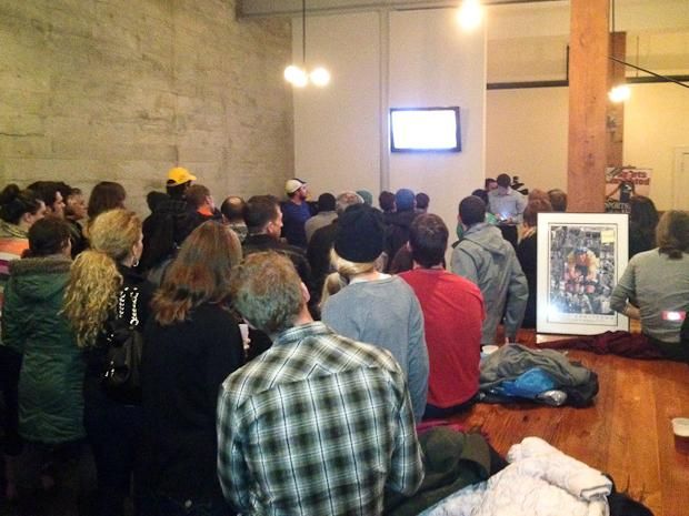 Cycling fans crowd around the TV in the lobby.