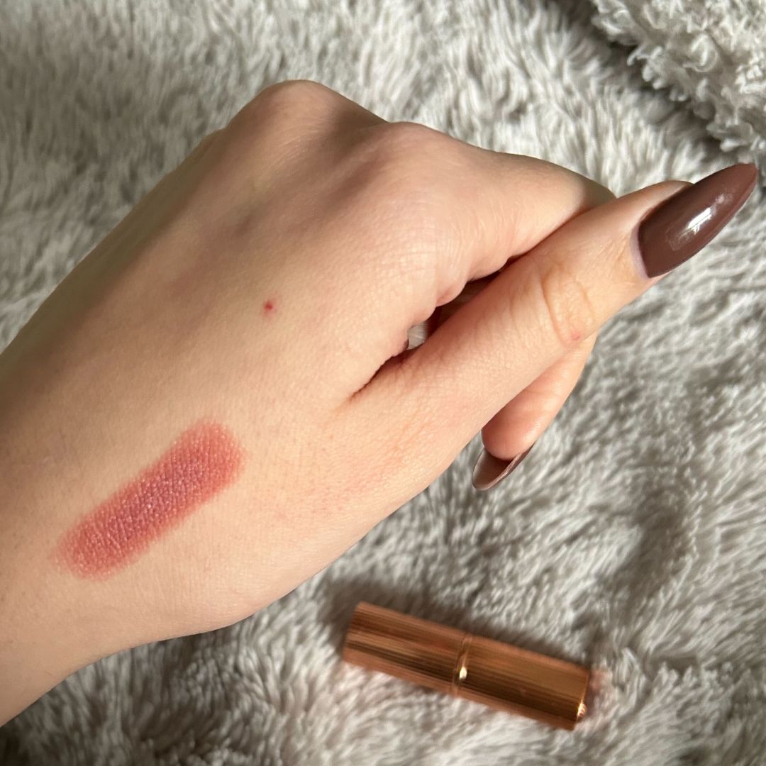 Swatch of Charlotte Tilbury Pillow Talk Lipstick on hand with brown nails