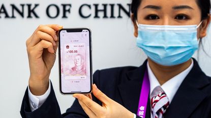 A worker shows China's digital currency on a smartphone