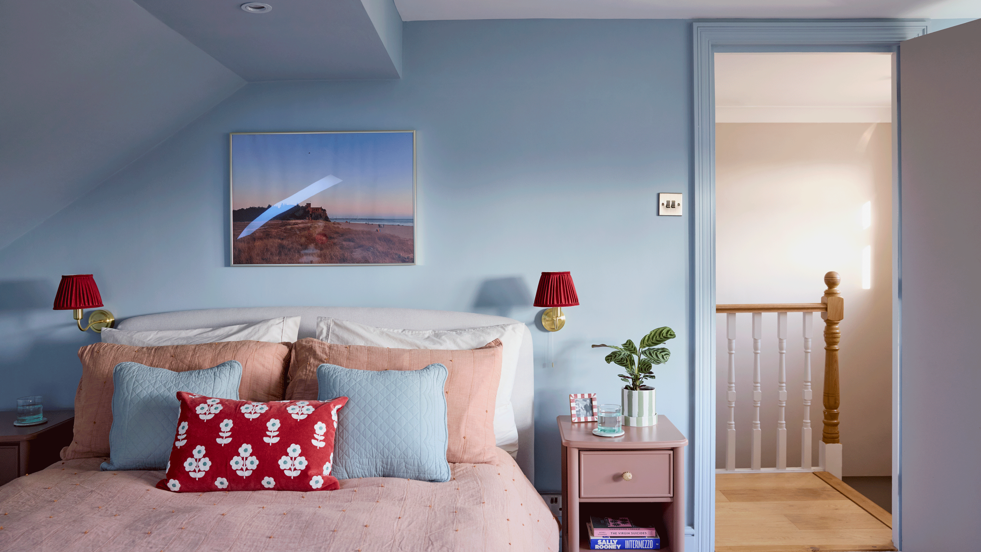 a blue and pink bedroom with pops of red with colourful accesories