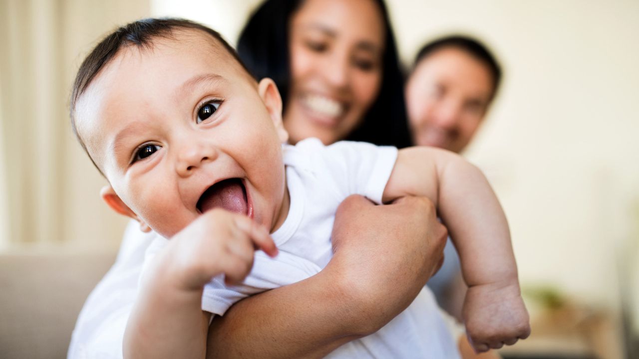 A mom and dad hold a smiling baby.