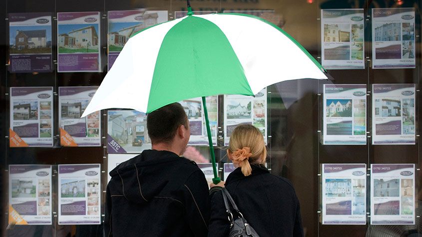 Couple looking in an estate agent&amp;#039;s window