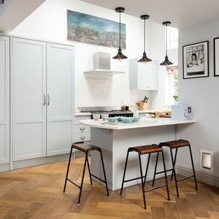 A galley kitchen with pale blue cabin, roof lantern and parquet flooring