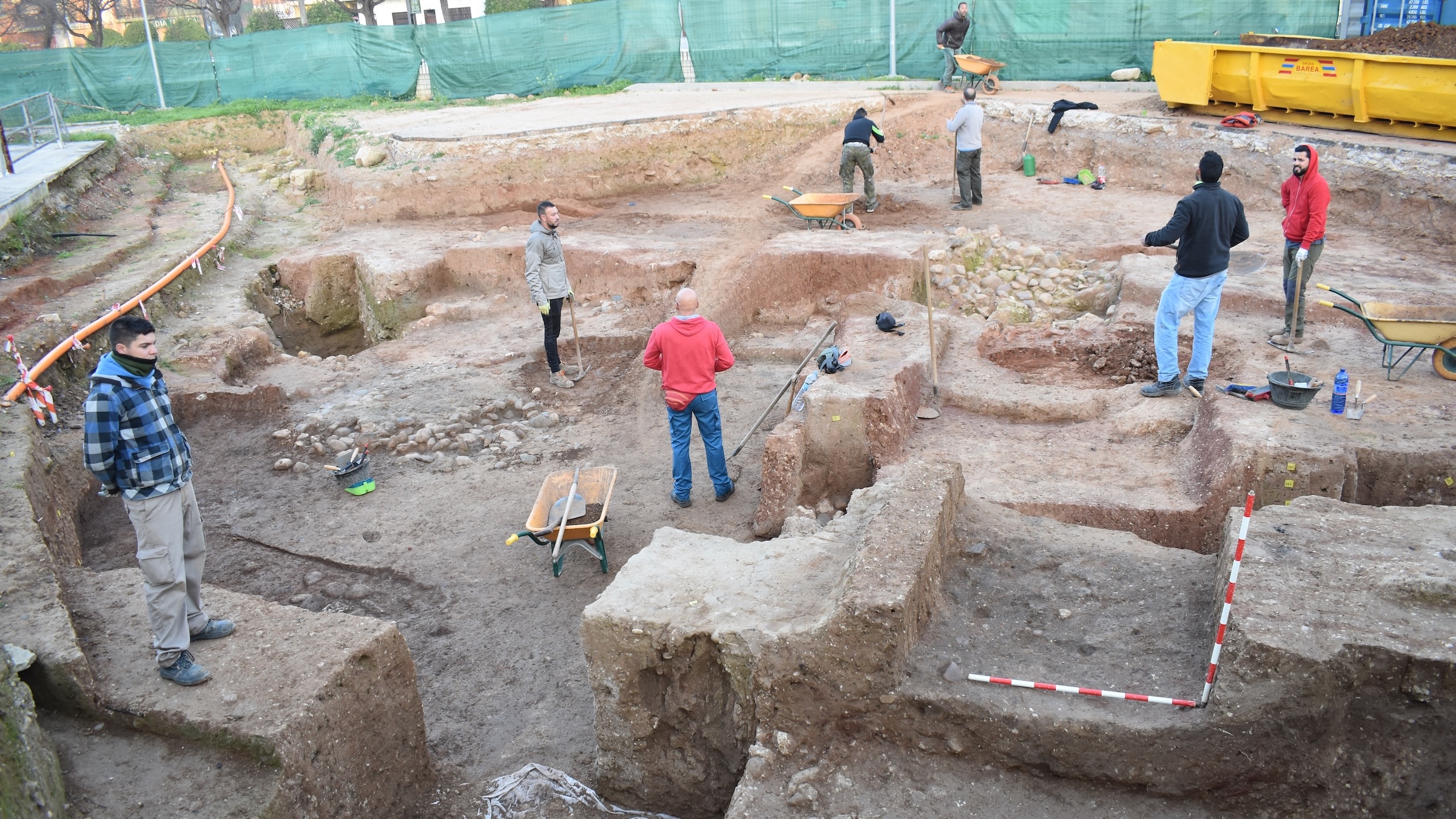 A group of people excavate on a dirt-covered area.