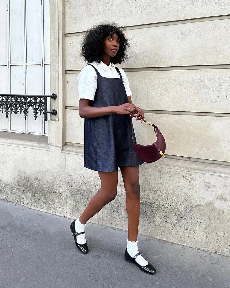 @emmanuellek_ wears a denim minidress layered over a white short sleeve shirt