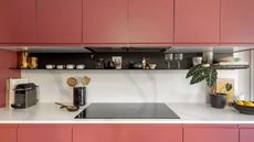 pink kitchen cabinetry with stove and shelving