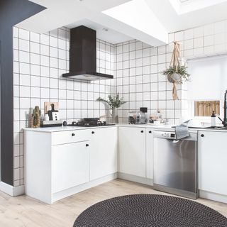 Small white L-shaped kitchen with black cooker hood and white tiles