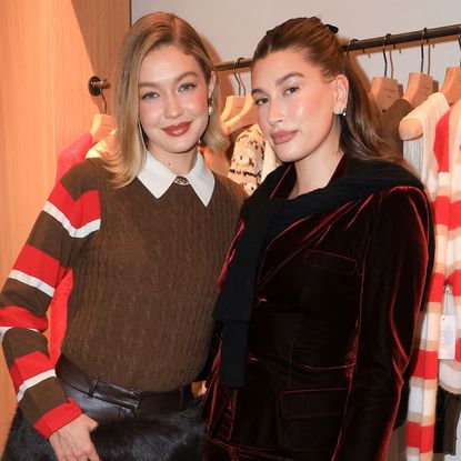 Gigi Hadid in a brown and red Guest in Residence Striped Rugby and Guest in Residence brown cashmere vest and Hailey Bieber in a burgundy velvet skirt and jacket at the Guest in Residence store opening in Los Angeles.