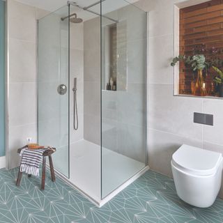 A bathroom with a shower and a toilet and a patterned floor