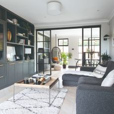 A living room with a dark grey built-in media unit and a tonal chaise sofa