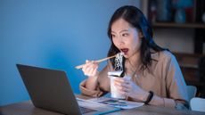 Woman eating dinner in front of a laptop