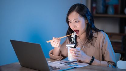 Woman eating dinner in front of a laptop