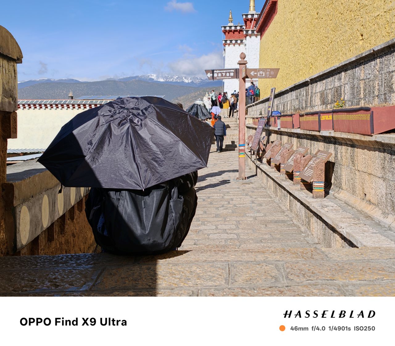 Person sat on a step in the sun, holding an umbrella