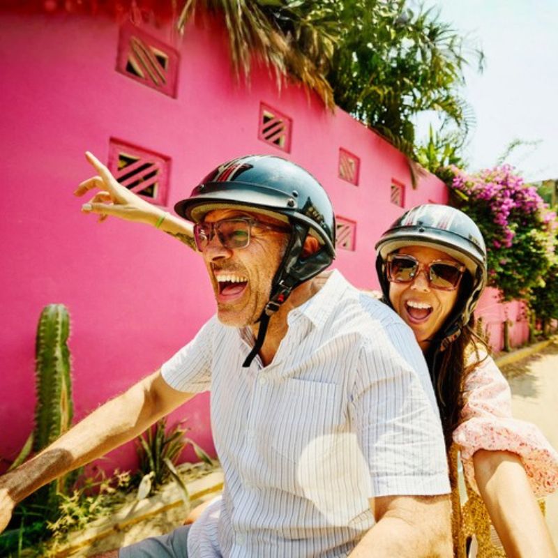 A couple riding a scooter while traveling on vacation.