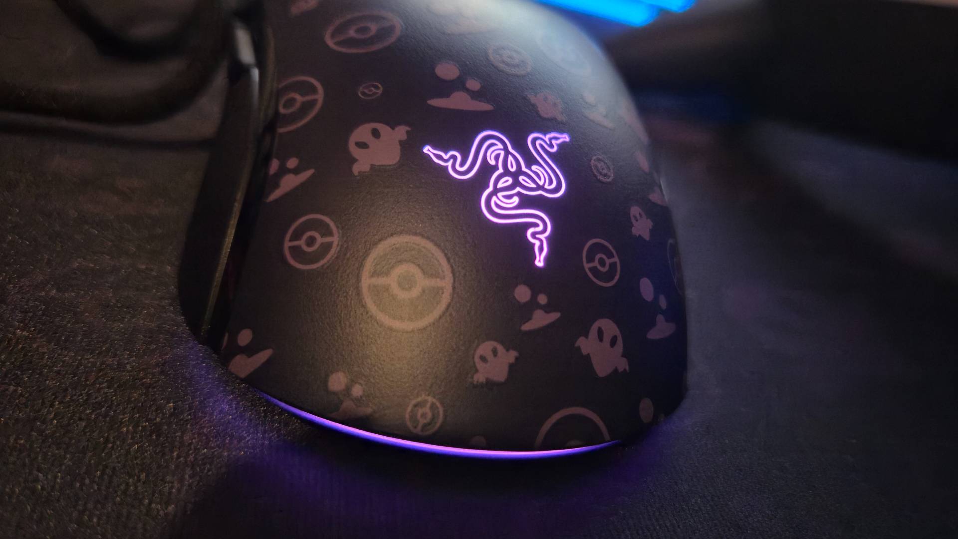 Close up of a purple light glowing from a gaming mouse, while it sits on a matching purple mousemat.