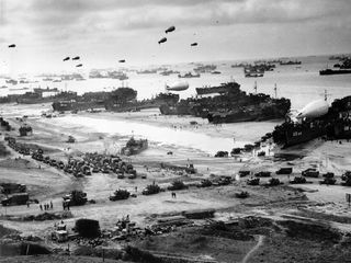 LSTs (Landing Ship Tanks), landing vehicles, and cargo on a Normandy beach, June 1944.