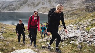 A group hiking uphill with a lake in the background