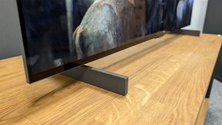 LG C4 42-inch OLED TV on wooden AV bench close up on feet and bottom of TV