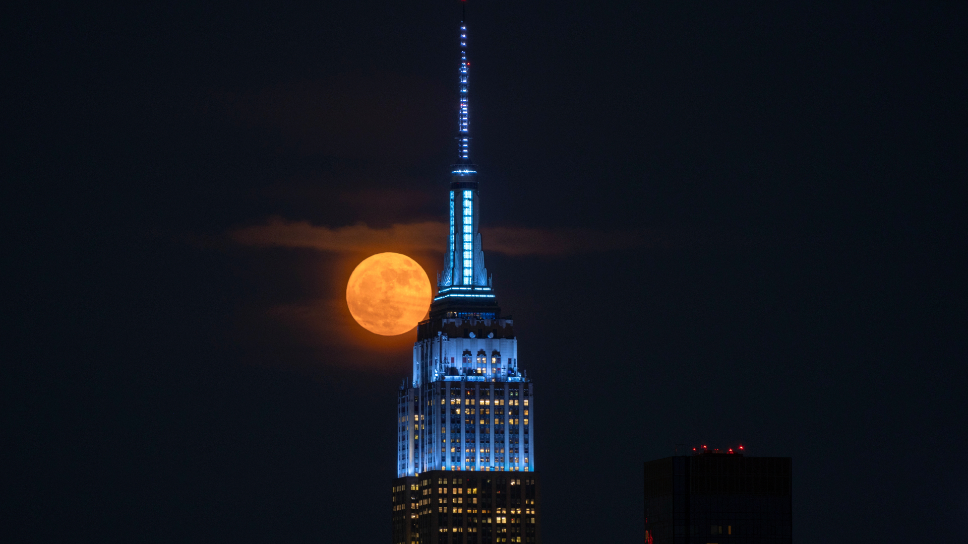 The full Strawberry Moon is pictured next to the spire of the Empire State Building skyscraper in New York.