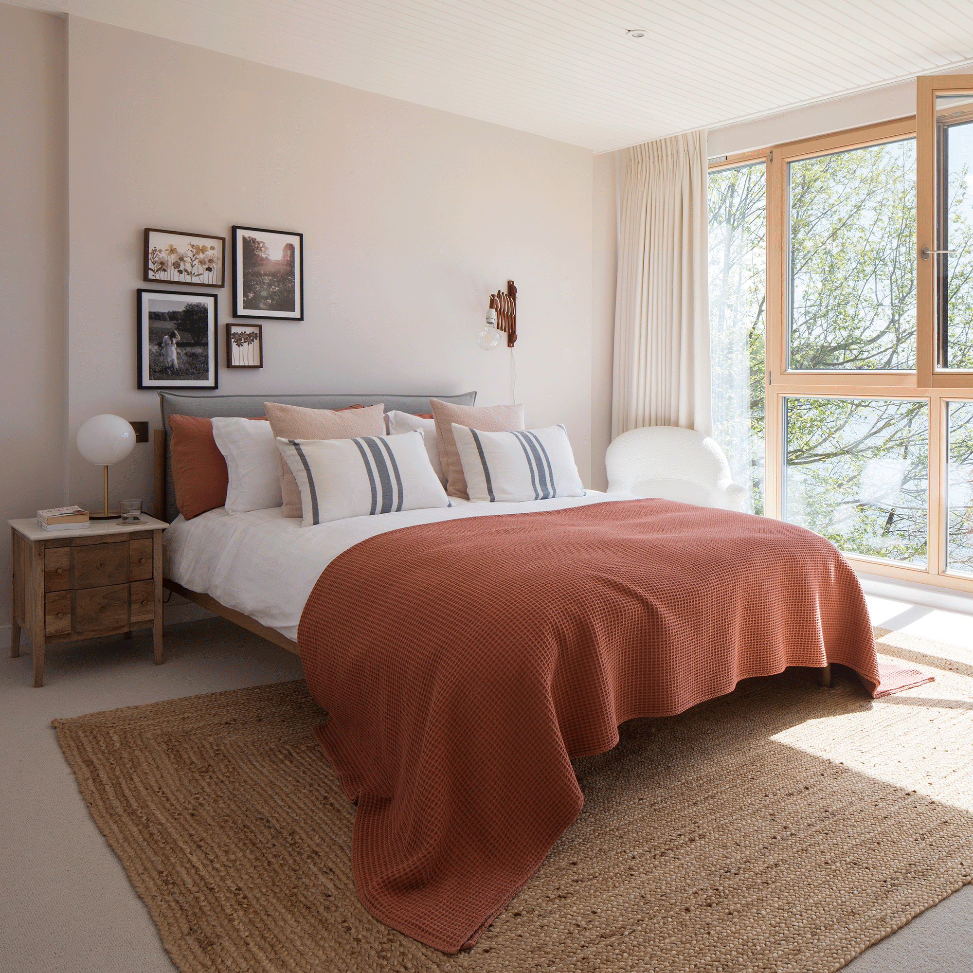 White bed with red throw on a natural rug
