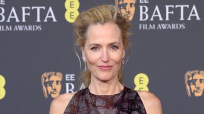 Gillian Anderson is pictured with a voluminous updo hairstyle and wearing a high-neck dress at the 2026 EE BAFTA Film Awards at The Royal Festival Hall on February 22, 2026 in London, England. 