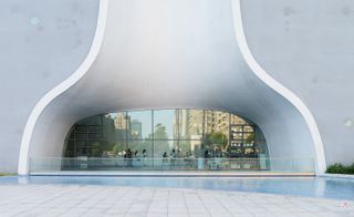Curved covered patio area of the National Taichung Theater with a water pool infront