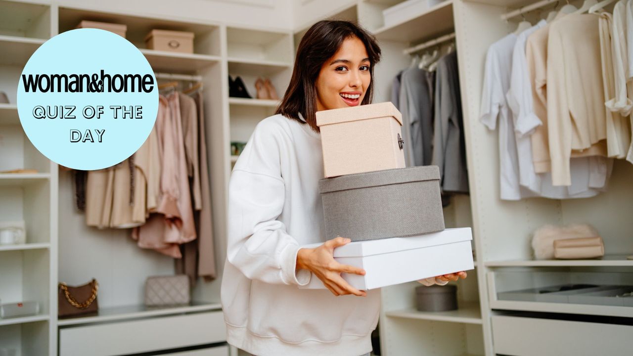 woman holding boxes in a large wardrobe and smiling 