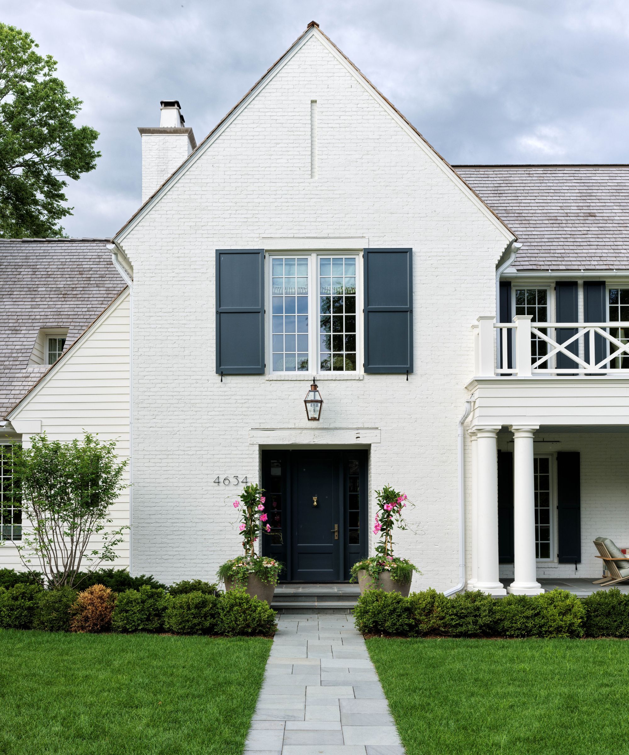 Exterior of a white home with blue shutters and first floor balcony