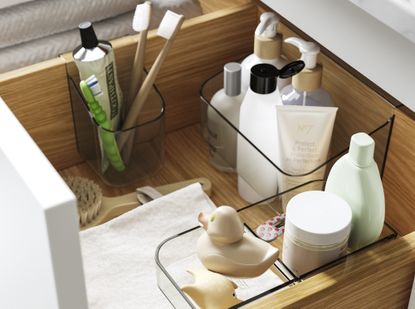 A neatly organized bathroom drawer with compartments for toothbrushes, skin care, rubber ducks and more