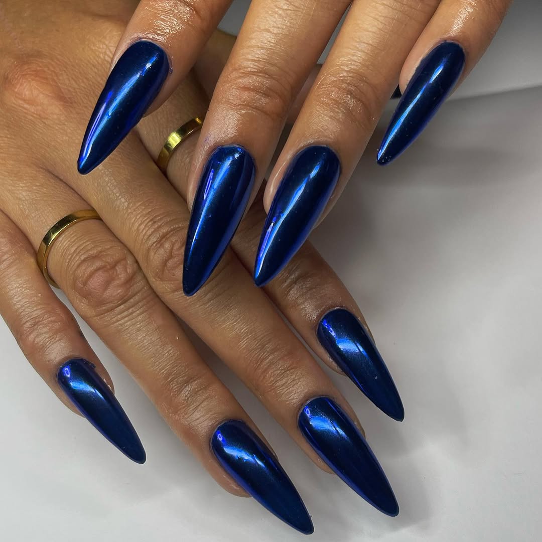 a person wearing pointy, dark blue chrome nails