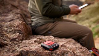 Photo of the Garmin InReach Messenger Plus and someone using it to send messages on their smartphone over satellite.