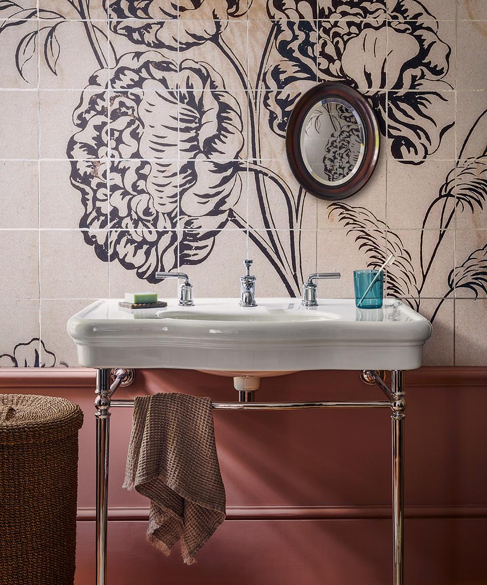 An example of bathroom paint ideas showing a traditional white sink in front of pink wall tiles with a floral wall mural